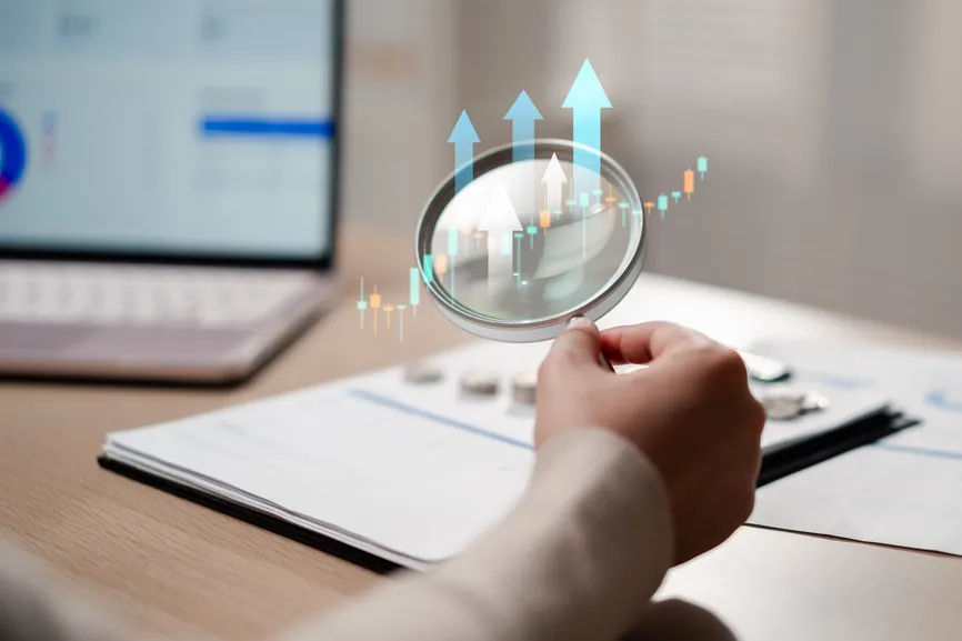 Magnifying glass over a report with rising growth arrows.