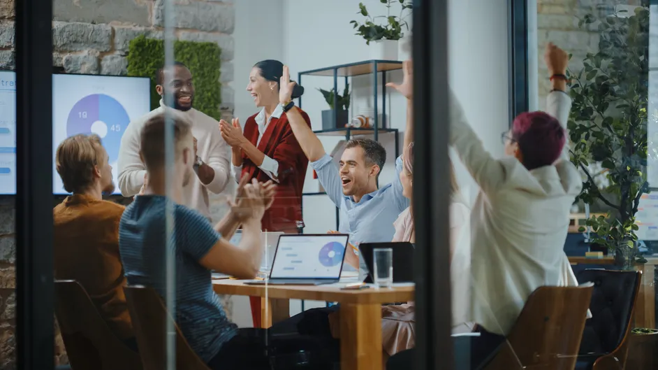 Team celebrating around a conference table.