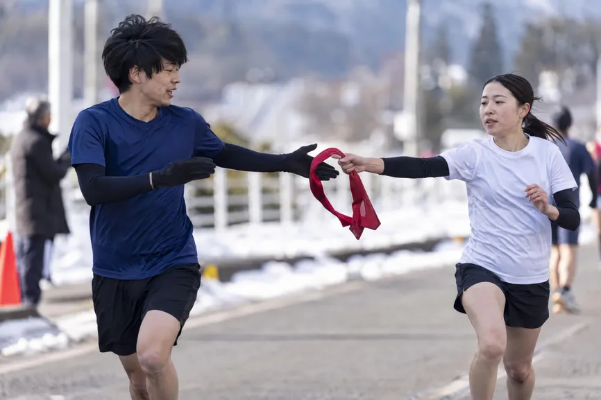 Relay runner passing a baton to a teammate.