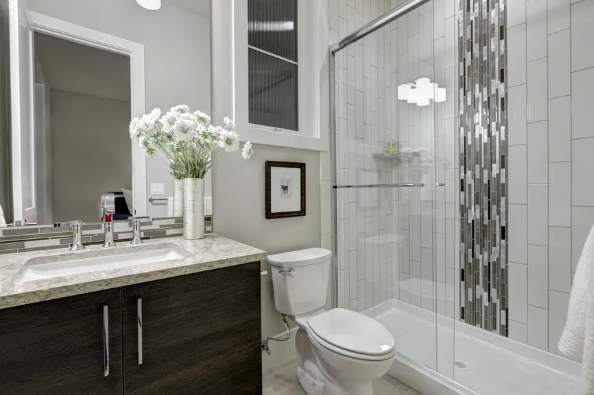 Remodeled bathroom with a glass shower and a tiled accent wall.