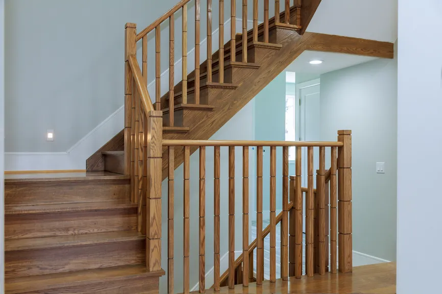 Finished wooden staircase with railings in a renovated home.