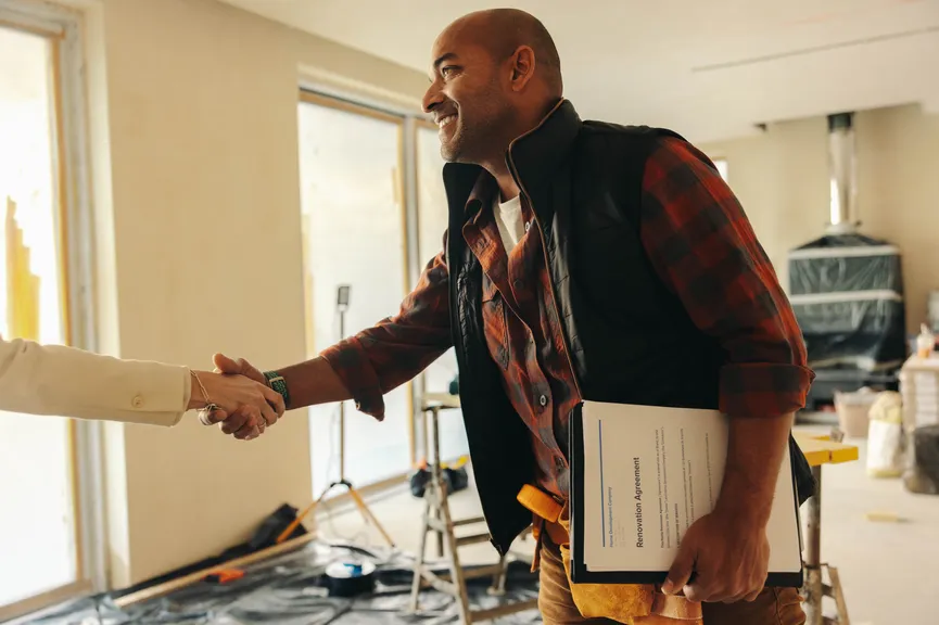 Contractor shaking hands with a client inside a home under renovation.