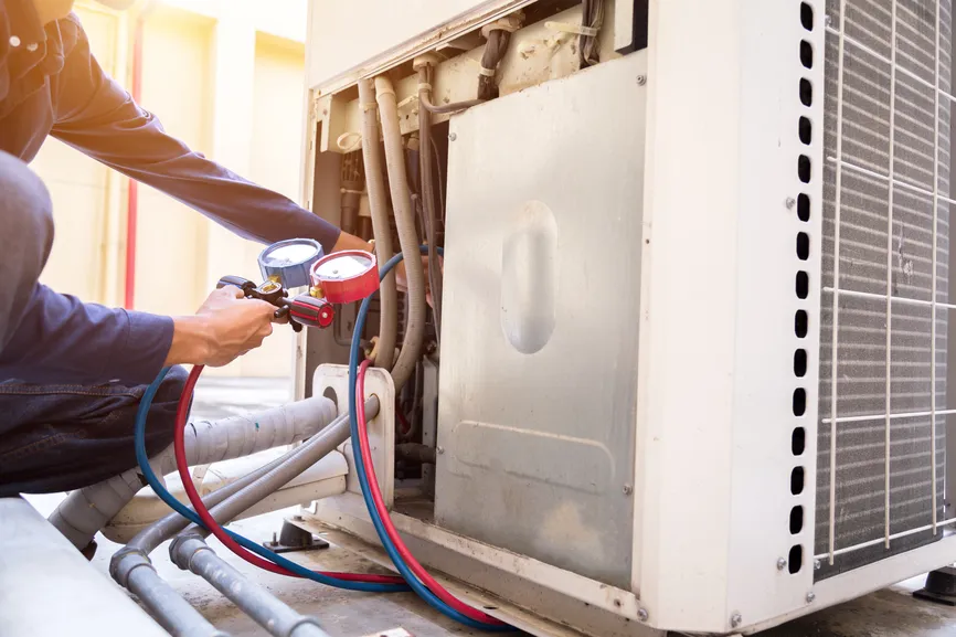 Technician connecting refrigerant gauges to an outdoor unit.