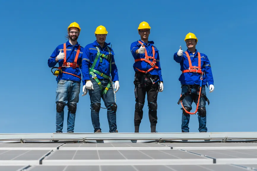 Roofing crew in safety harnesses standing on a rooftop.