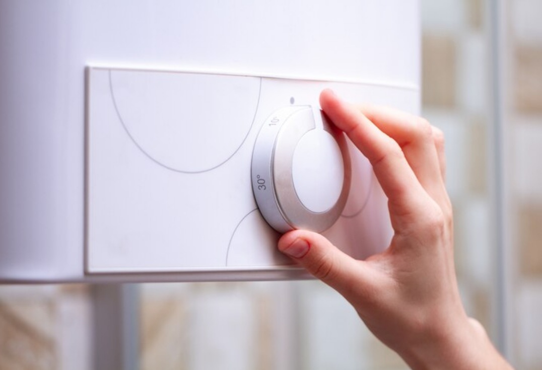 Hand adjusting water heater dial