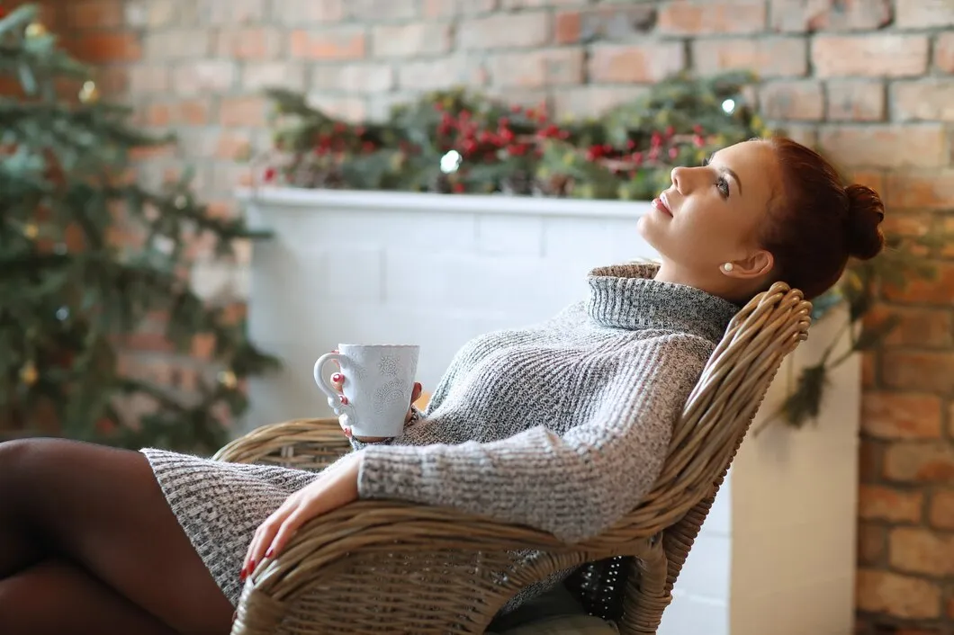 Woman relaxing with mug by fireplace