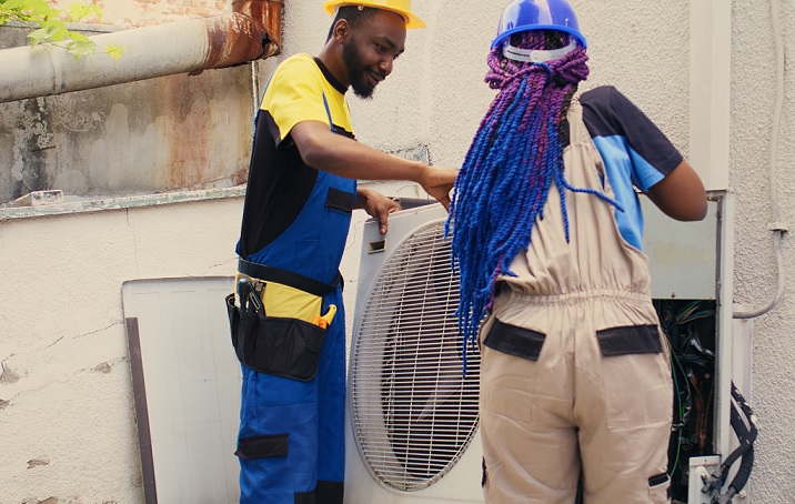 HVAC technicians working on an outdoor AC unit.