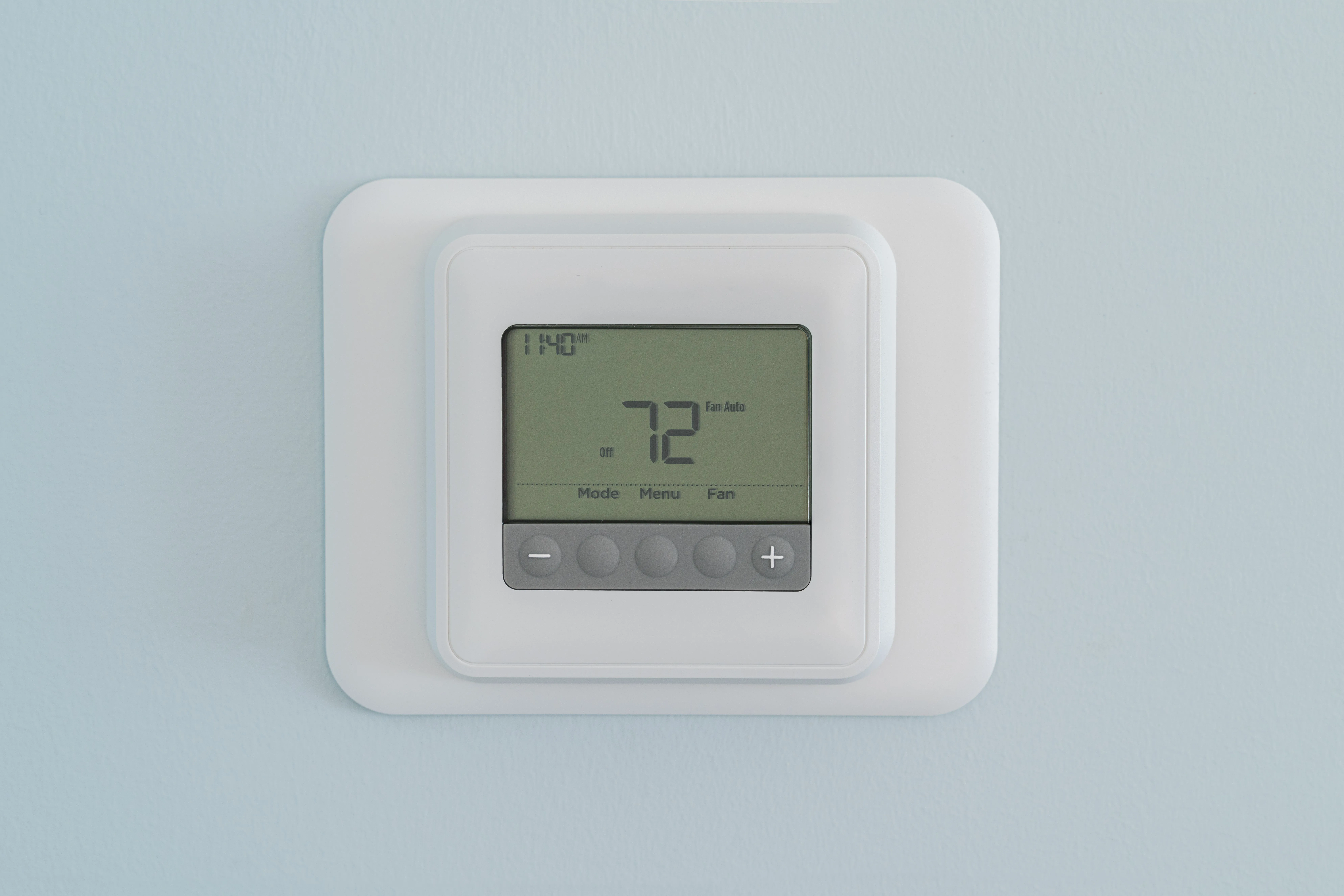 White digital thermostat on blue wall.
