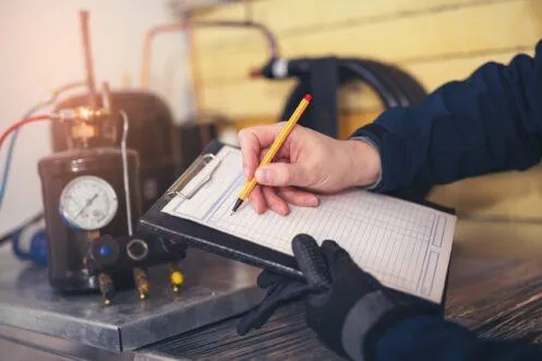 Person writing on a clipboard with machinery in background
