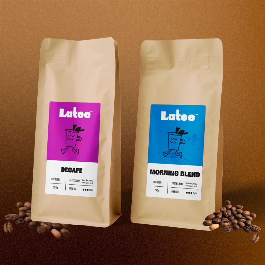 Two beige coffee bags labeled Latee, one with a purple label for Decafe espresso and one with a blue label for Morning Blend plunger, both with tasting notes and medium strength icons, set against a brown background with coffee beans at the base of each bag.
