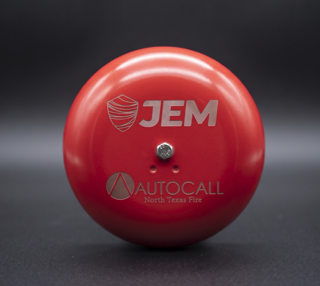 Close-up of a red fire alarm bell with JEM and AUTOCALL North Texas Fire logos.