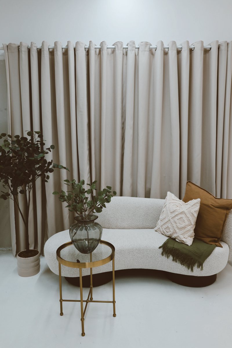 Cream bouclé sofa with gold side table and eucalyptus
