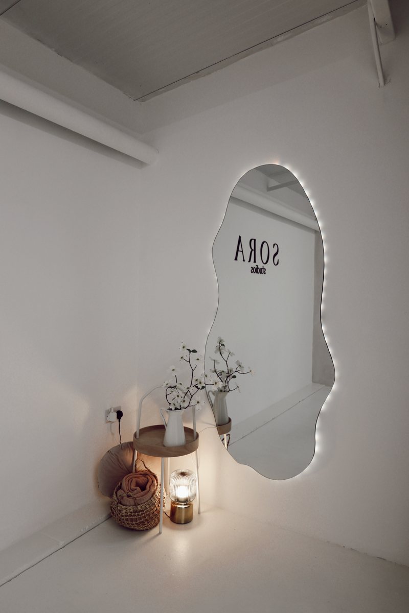 LED-backlit abstract mirror reflecting the Sora logo