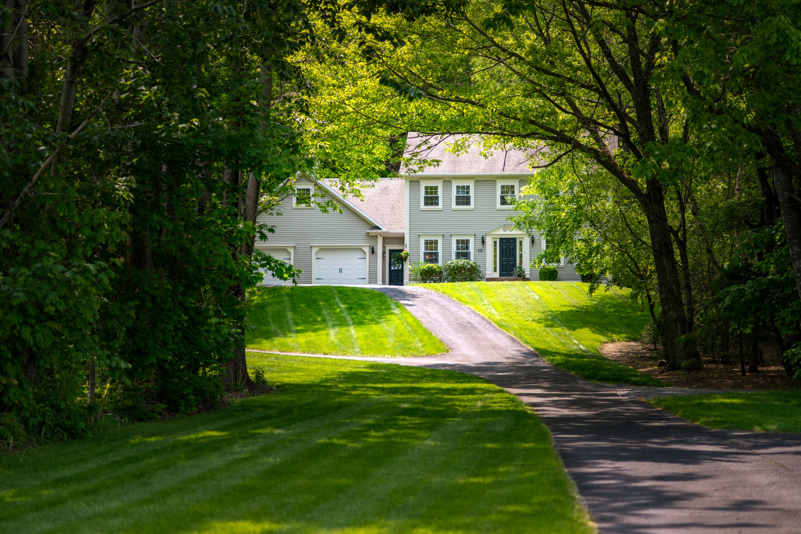 Colonial-style home at the end of a tree-lined driveway, listing photo by Newlife Studio