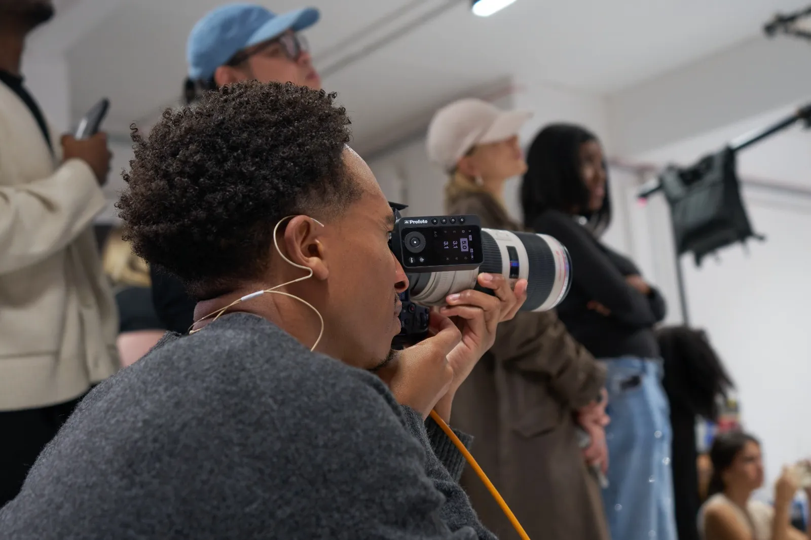 A maker looks through his camera with a wireless flash trigger while participants watch, at a Behind the Shoot masterclass