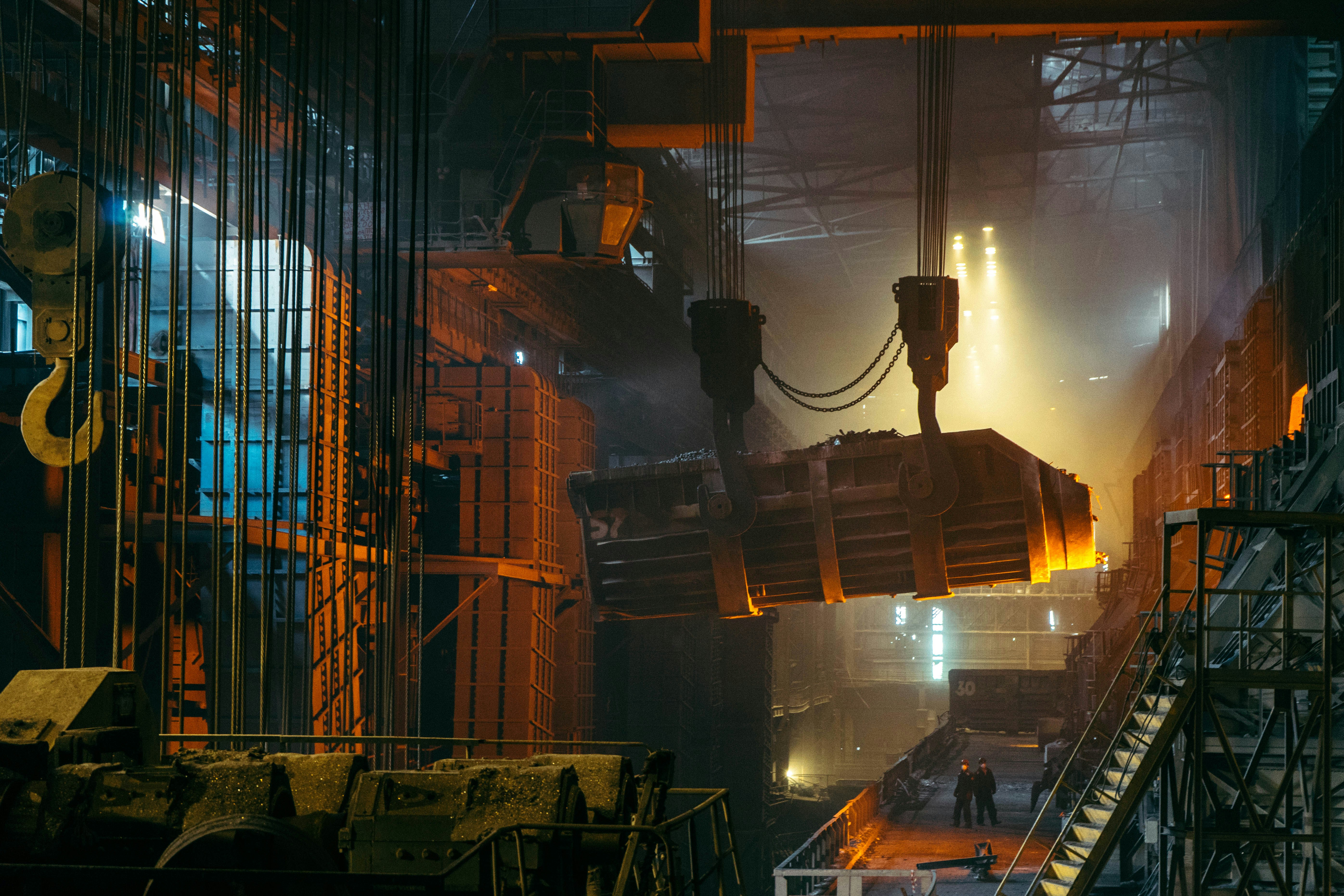Crane lifting a molten metal ladle in a steel mill