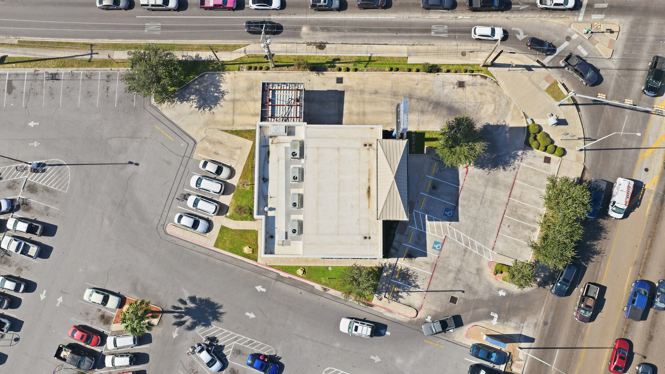 Aerial view of a commercial building, parking lots, and city streets