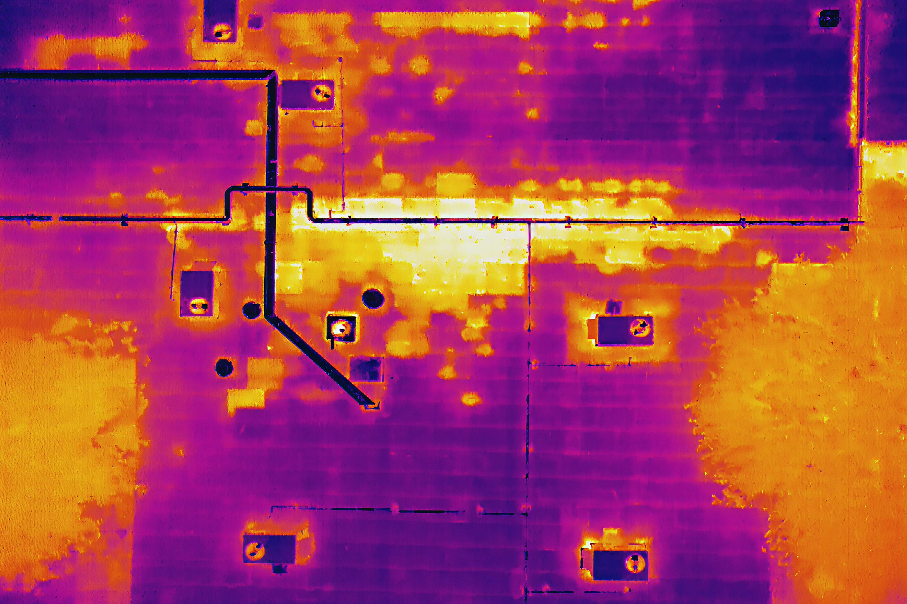 Thermal image of a rooftop showing heat distribution with warm yellow and orange areas and cooler purple zones.