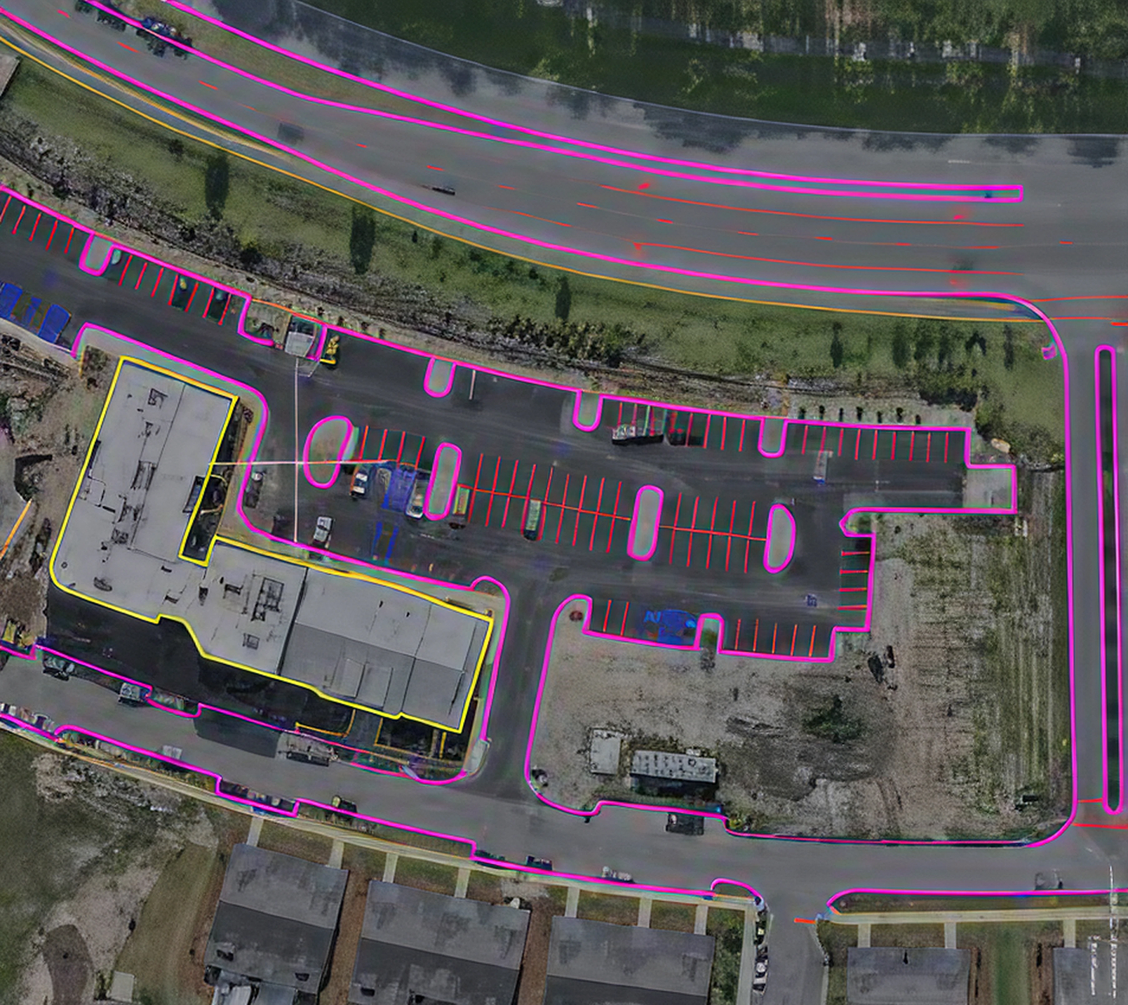 Orthomosaic map of a commercial building and parking lot with site plan linework overlaid in pink and yellow.