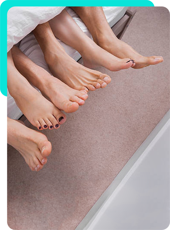 Three people's feet together at the end of a bed