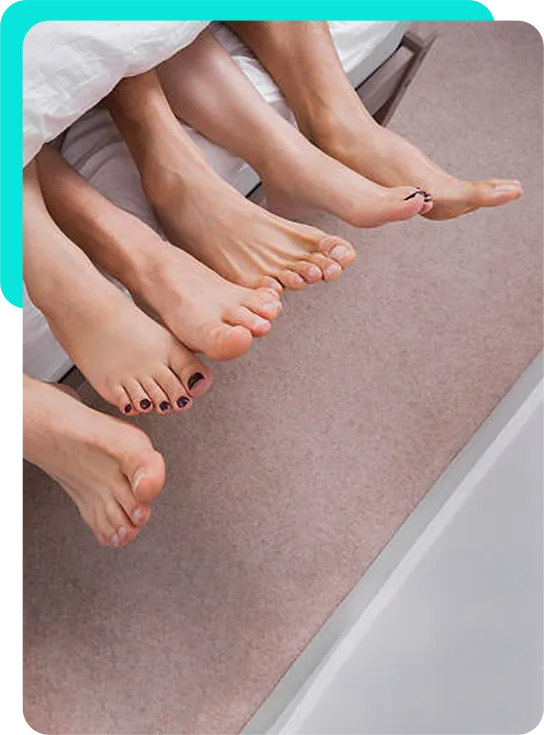 Three people's feet together at the end of a bed