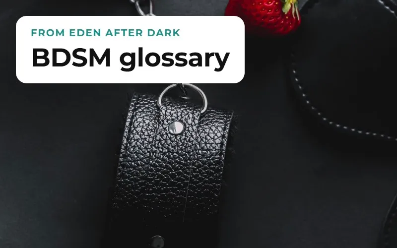 A leather wrist cuff with a chain, beside a strawberry