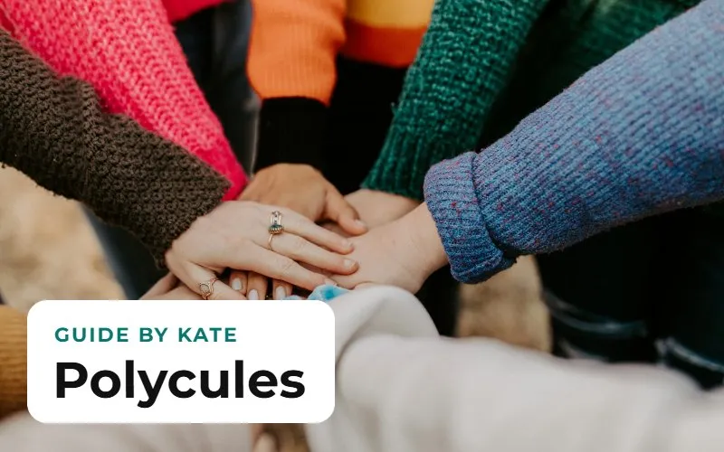 Several people's hands stacked together, in colorful sweaters