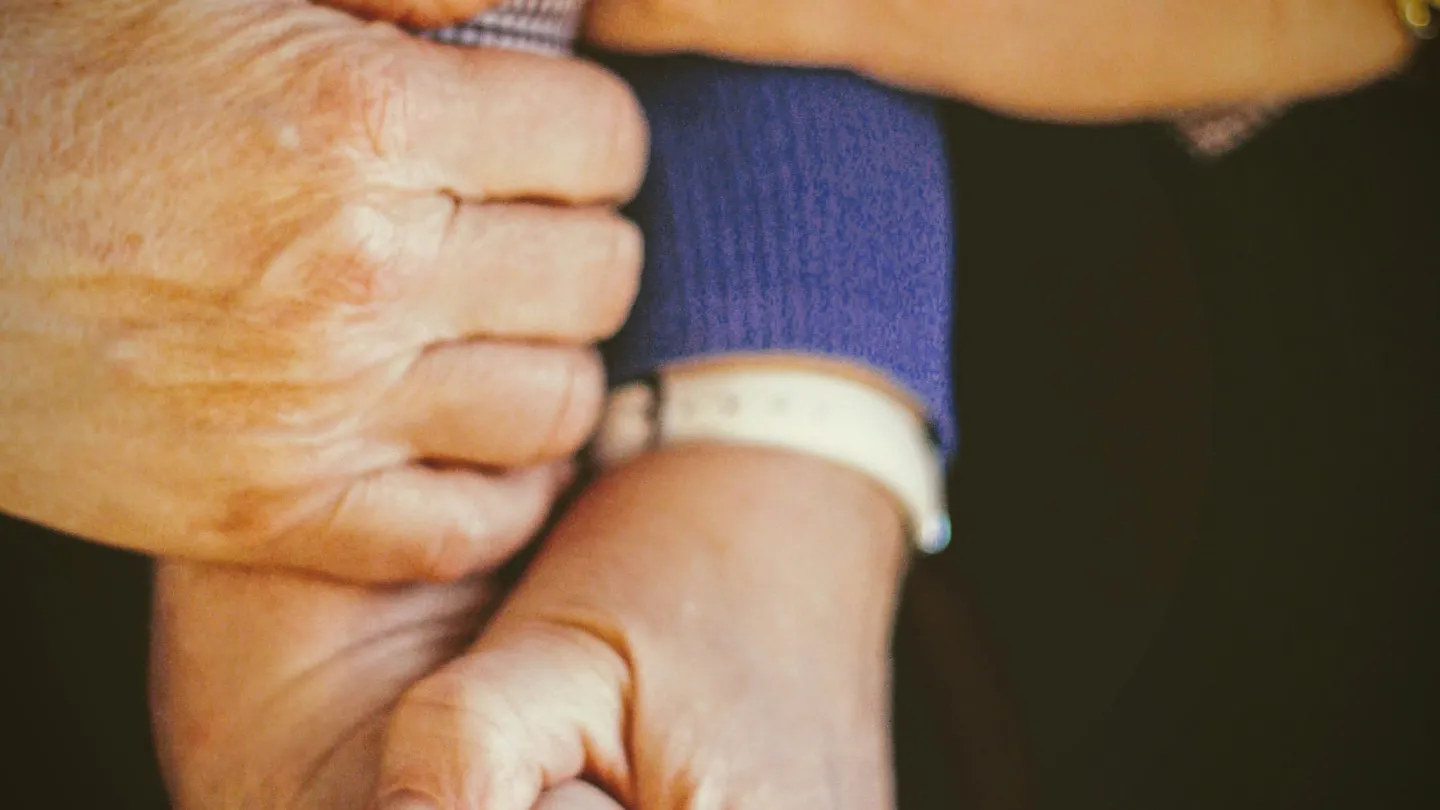 Hands of three people holding on to each other