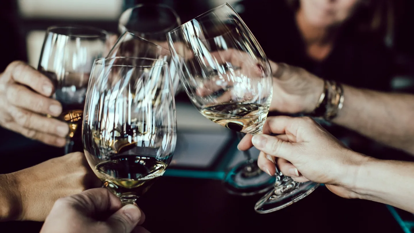 Several hands raising wine glasses over a shared table