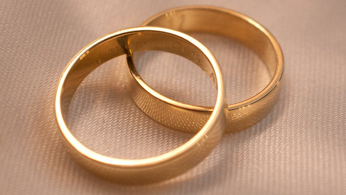 Two gold wedding rings resting on fabric