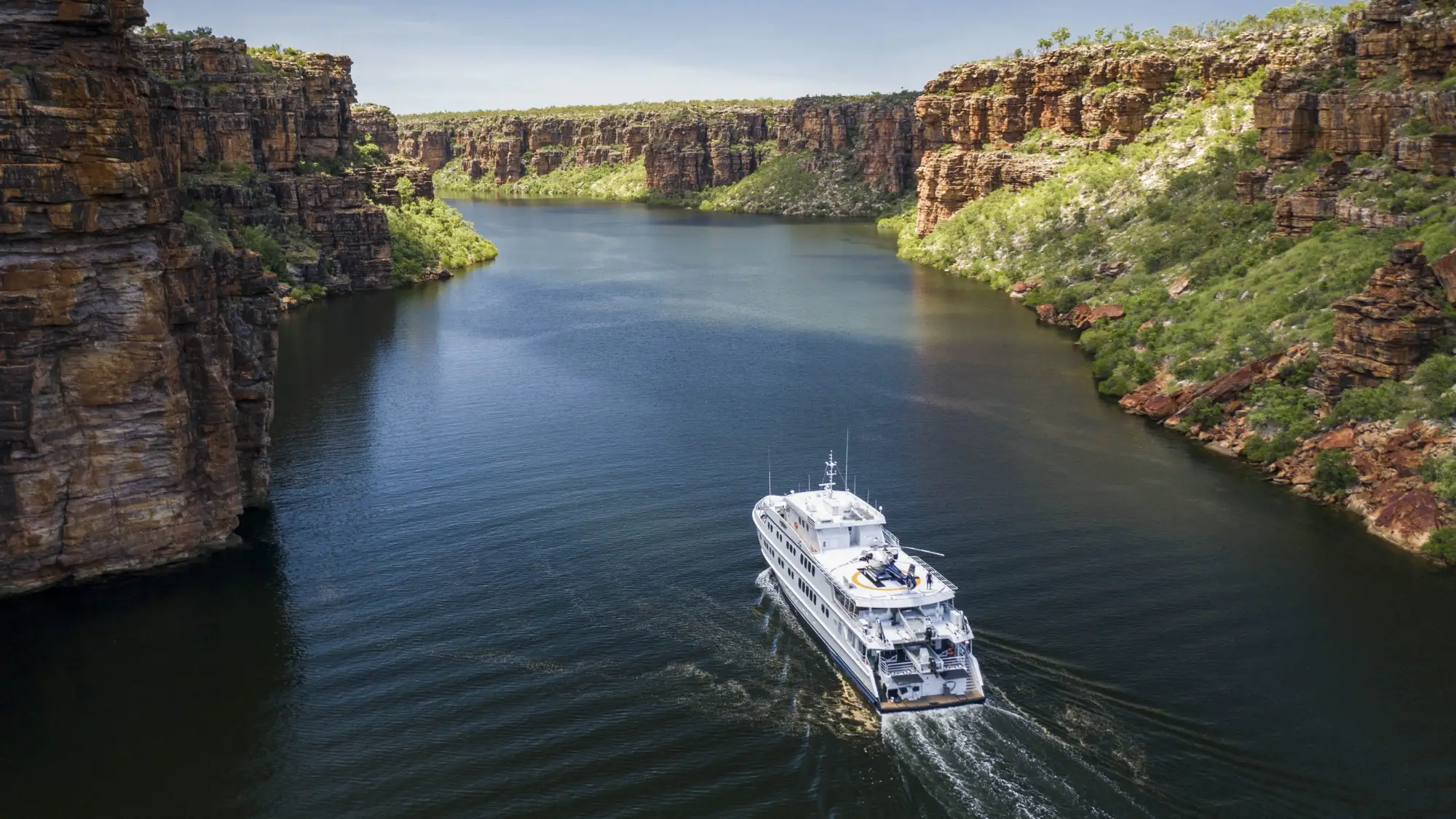 Expedition ship cruising a Kimberley river gorge between sandstone cliffs