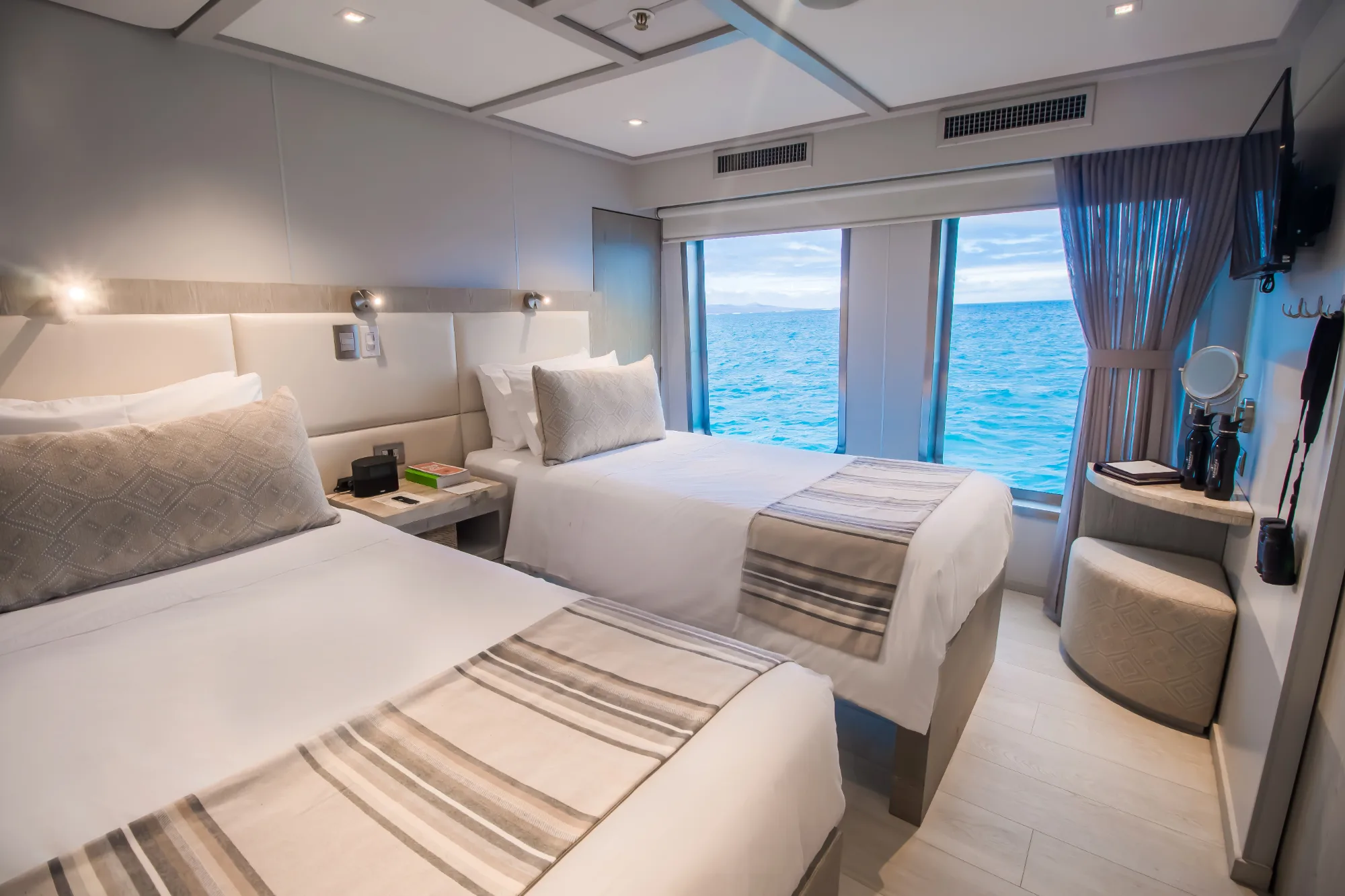 Deluxe stateroom with twin beds and an ocean-view window