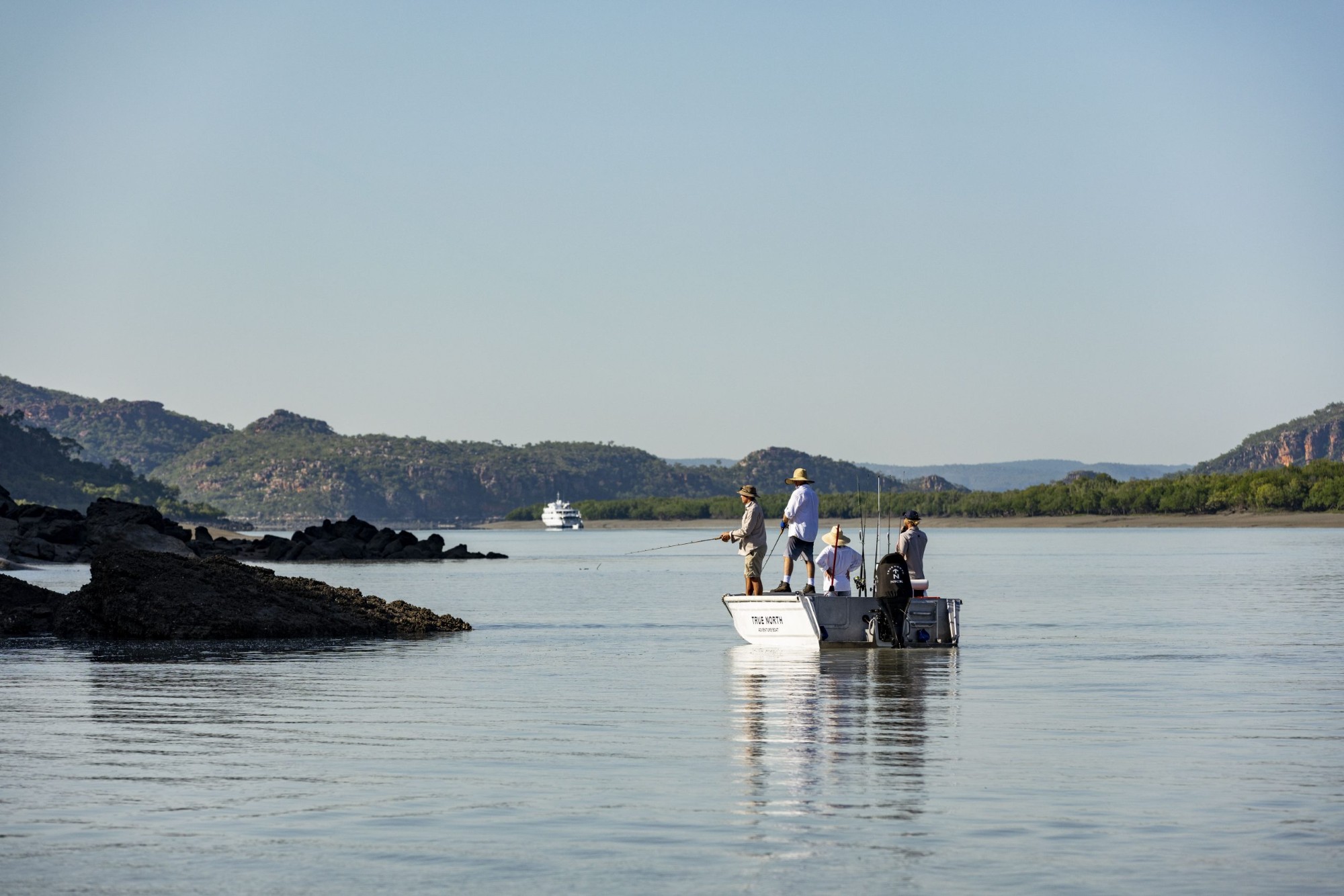 Guests fishing from an adventure boat with True North anchored upriver