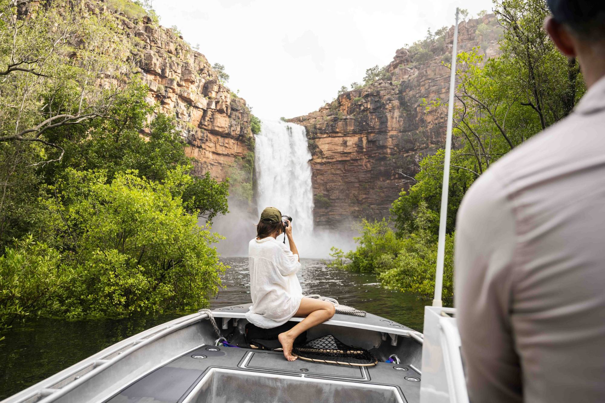 Guest photographing a waterfall from the bow of a tender in a Kimberley gorge