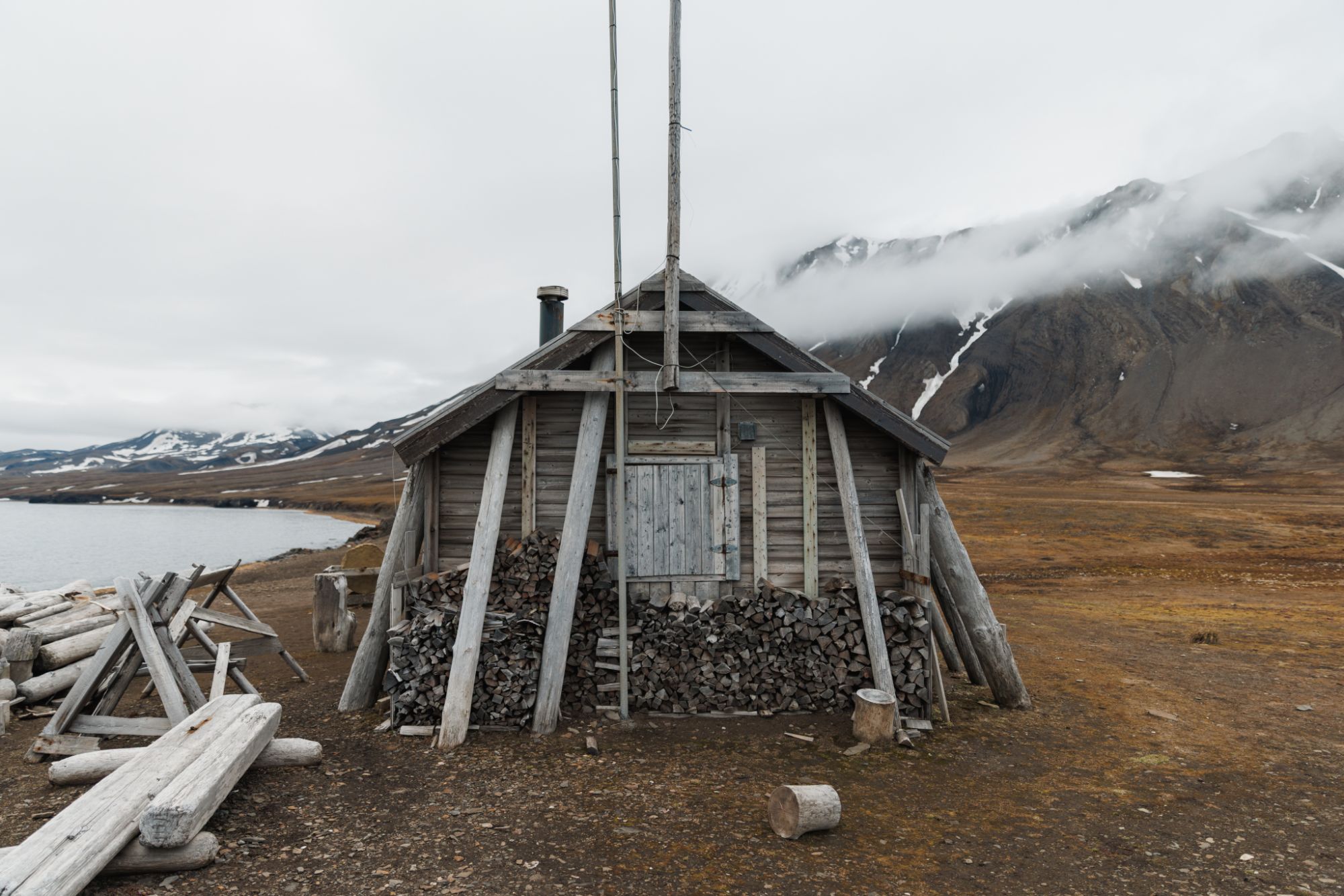Weathered trapper’s hut with stacked firewood on the Svalbard tundra