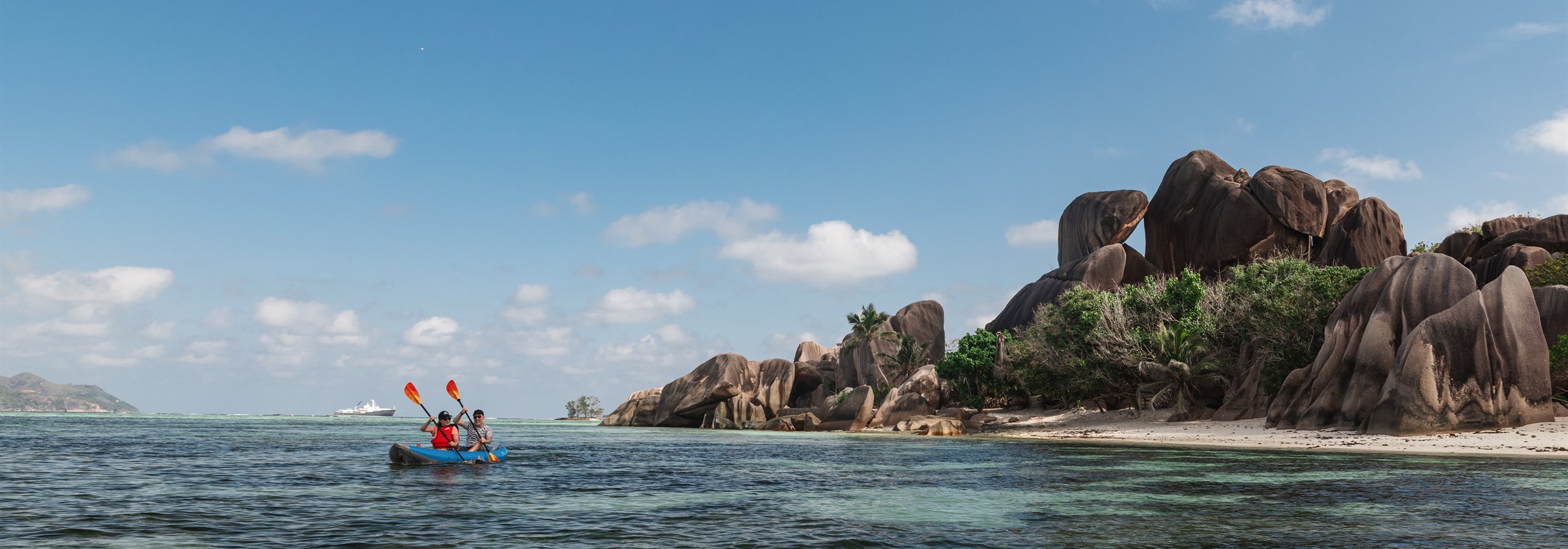 Guests kayaking past granite boulders on La Digue