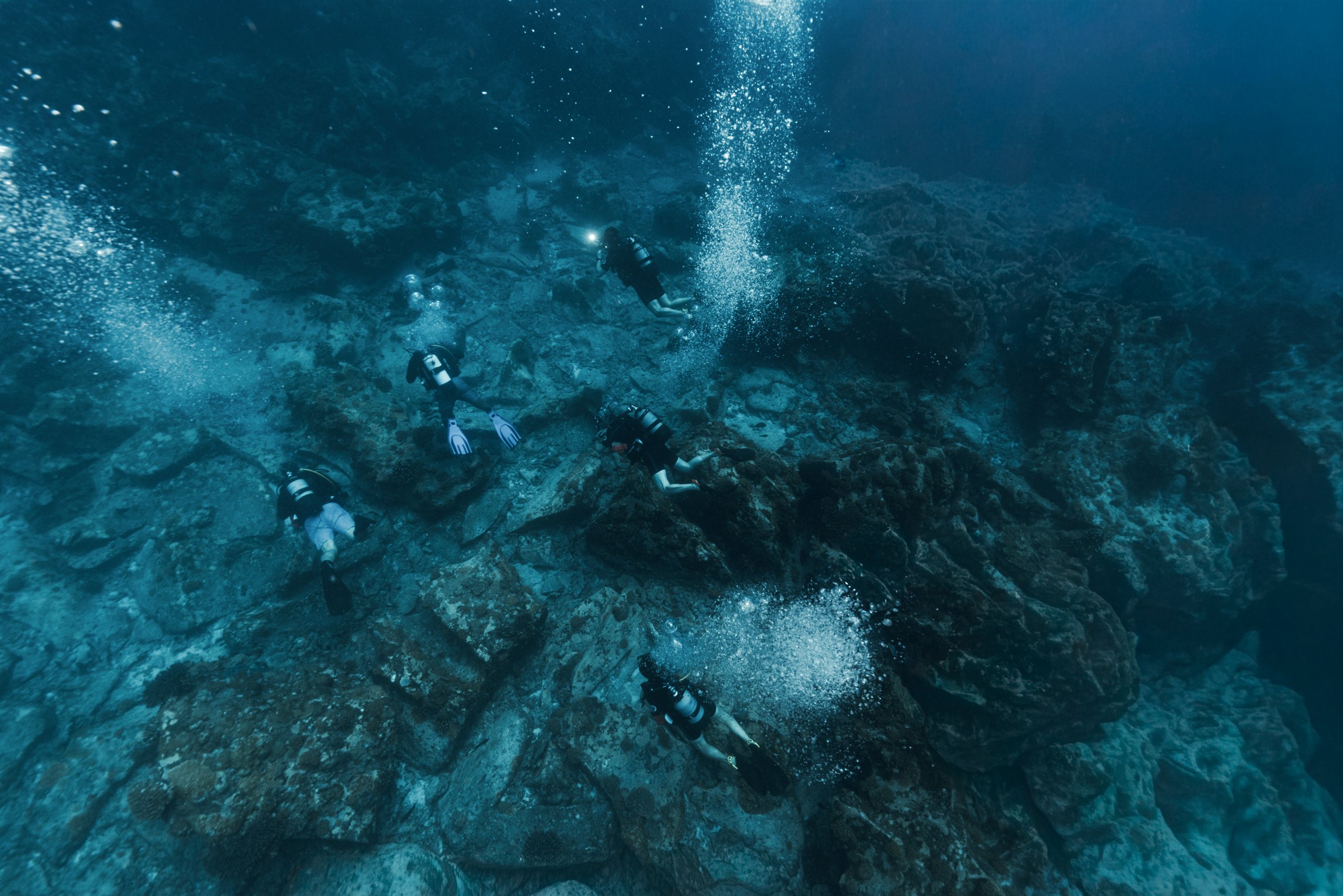 Divers descending along a coral wall