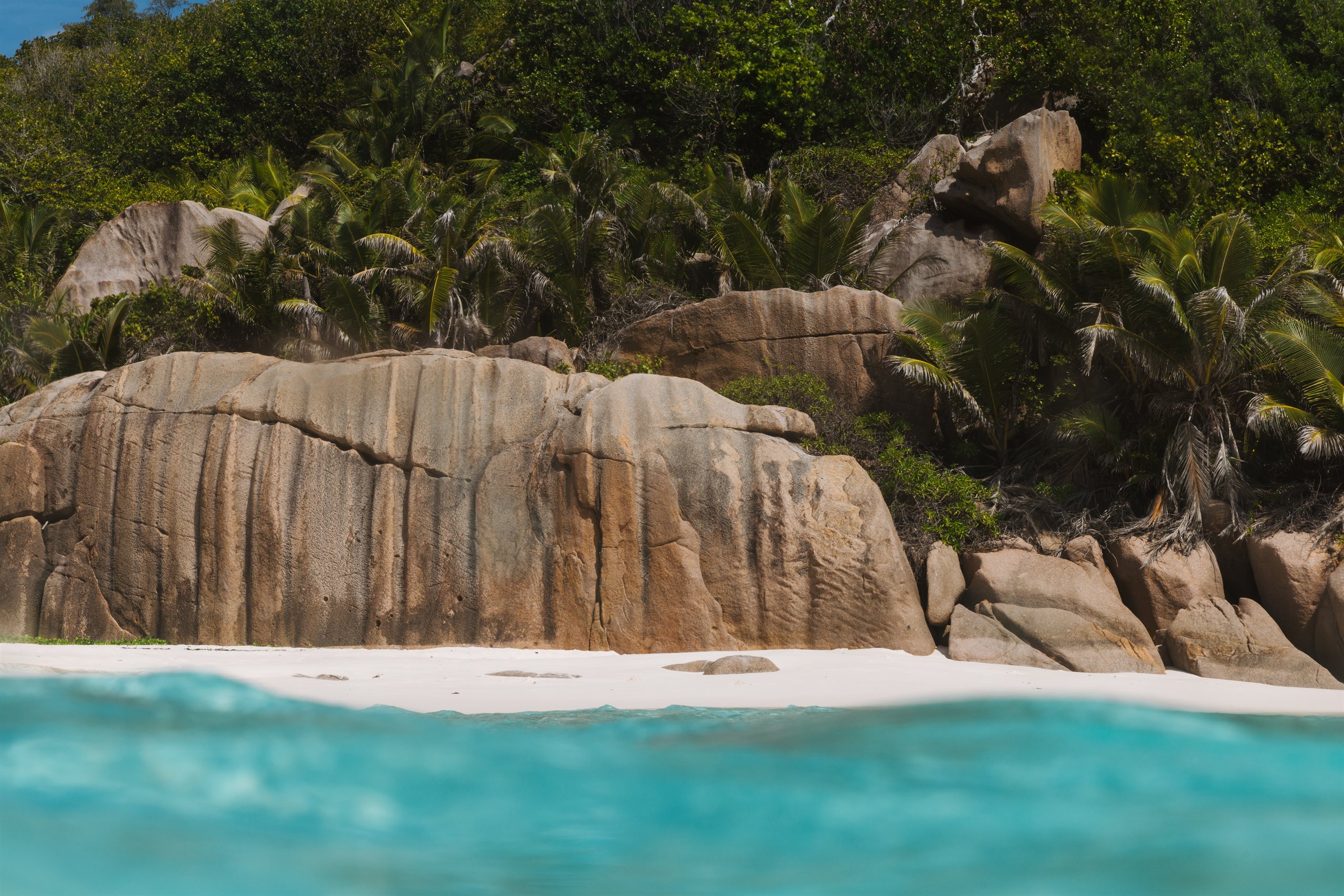 Weathered granite boulders above a white-sand beach
