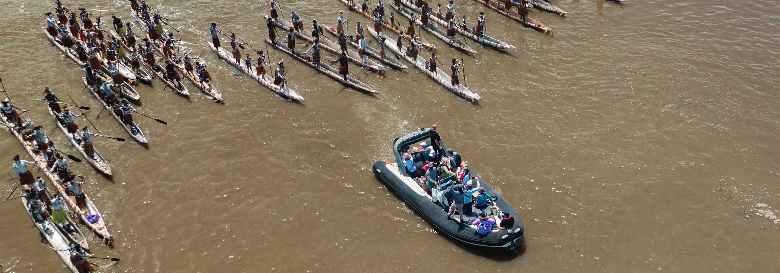Asmat canoes on a river beside a speedboat