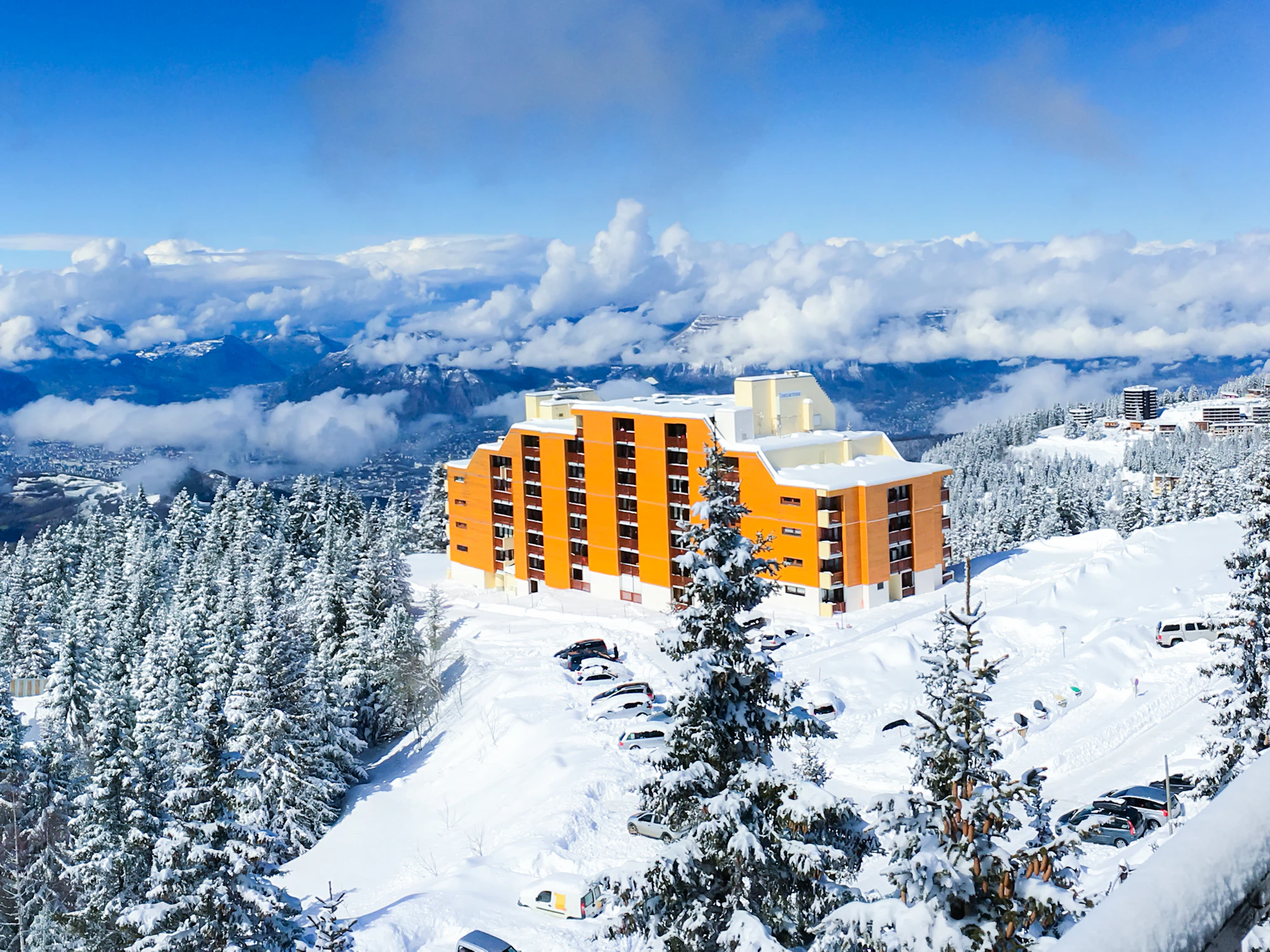 Résidence de la station de Chamrousse dans la forêt enneigée, au-dessus d’une mer de nuages