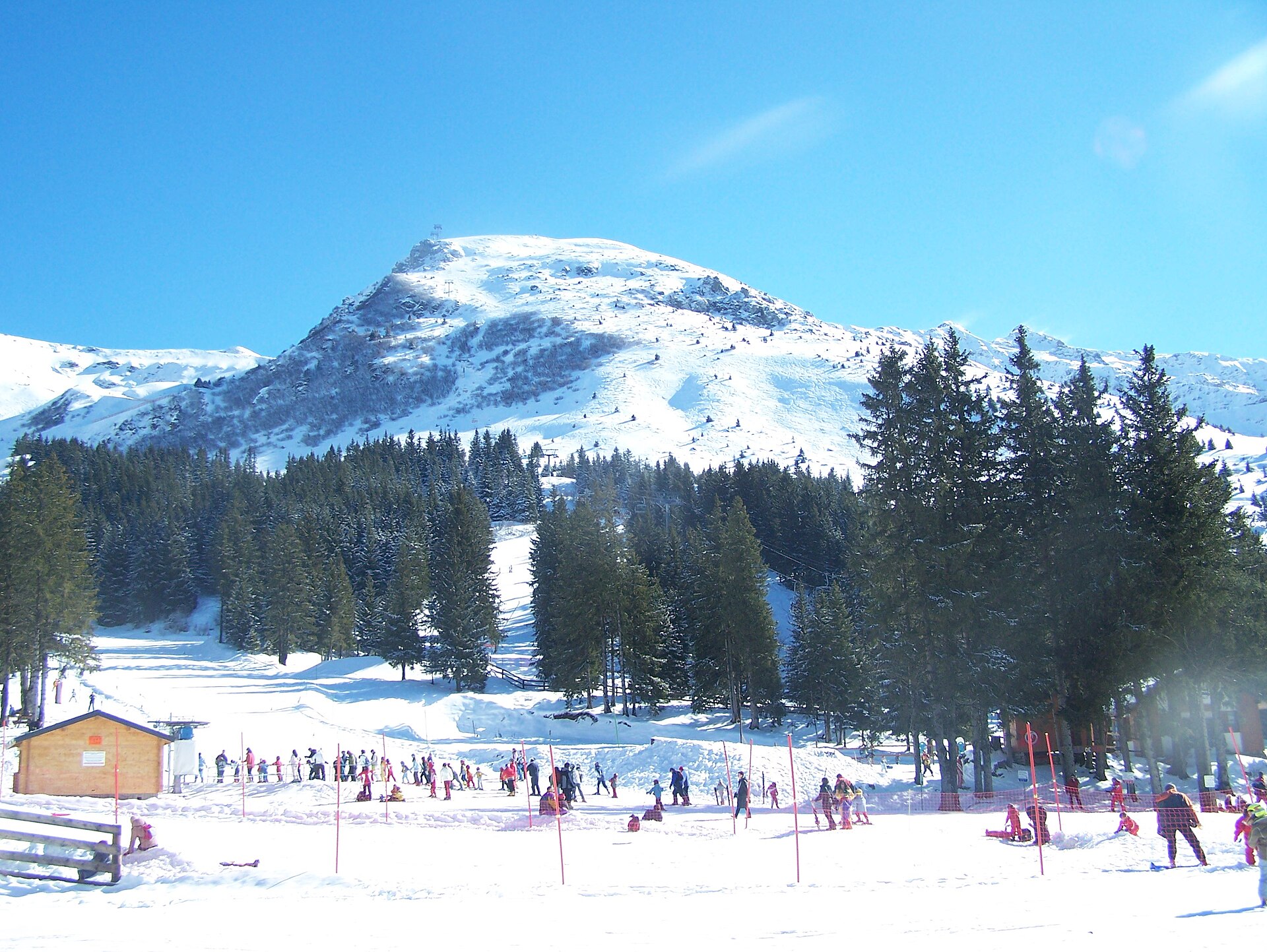 Pistes enneigées de la station des 7 Laux au pied d’un sommet de Belledonne, sous un ciel bleu