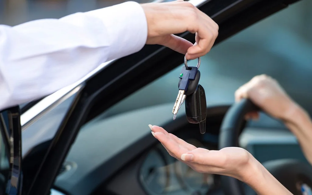 Car keys being handed to a driver through the car window