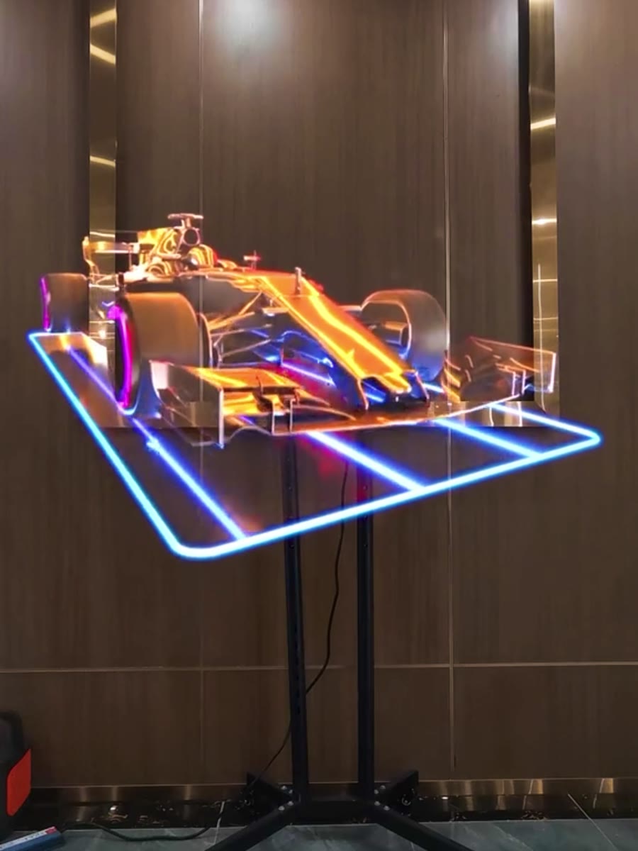 HOLOFAN MAX displaying a floating 3D race car hologram in a showroom