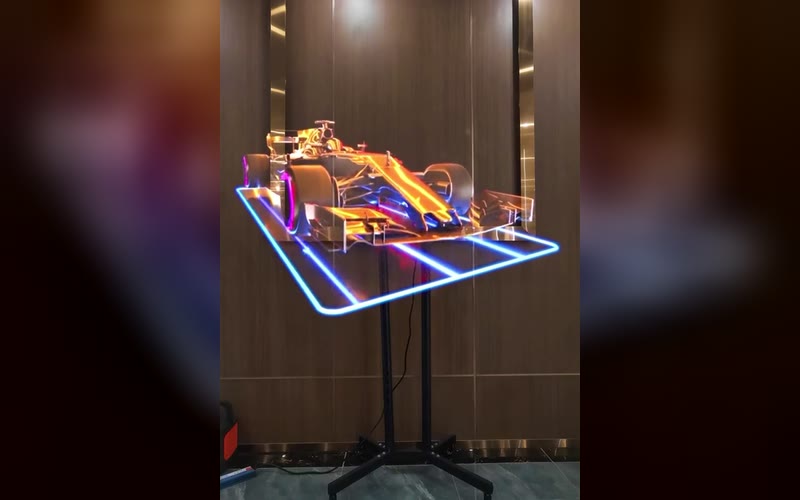 HOLOFAN MAX on a floor stand showing a 3D race car hologram in a lobby