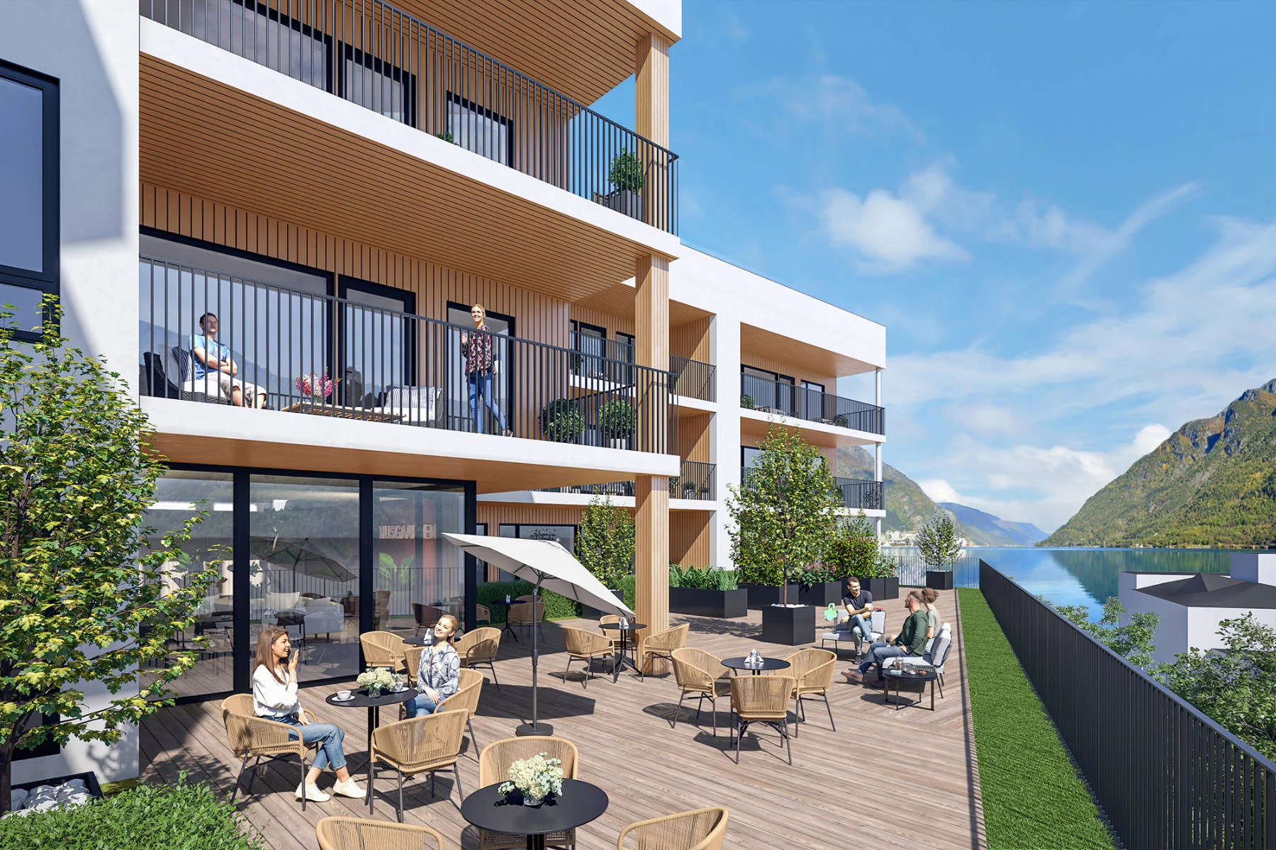Felles uteplass med sittegrupper og utsikt mot fjorden. Store balkonger i tre og glass gir lune uterom for alle beboerne i Domus Gaarden.
