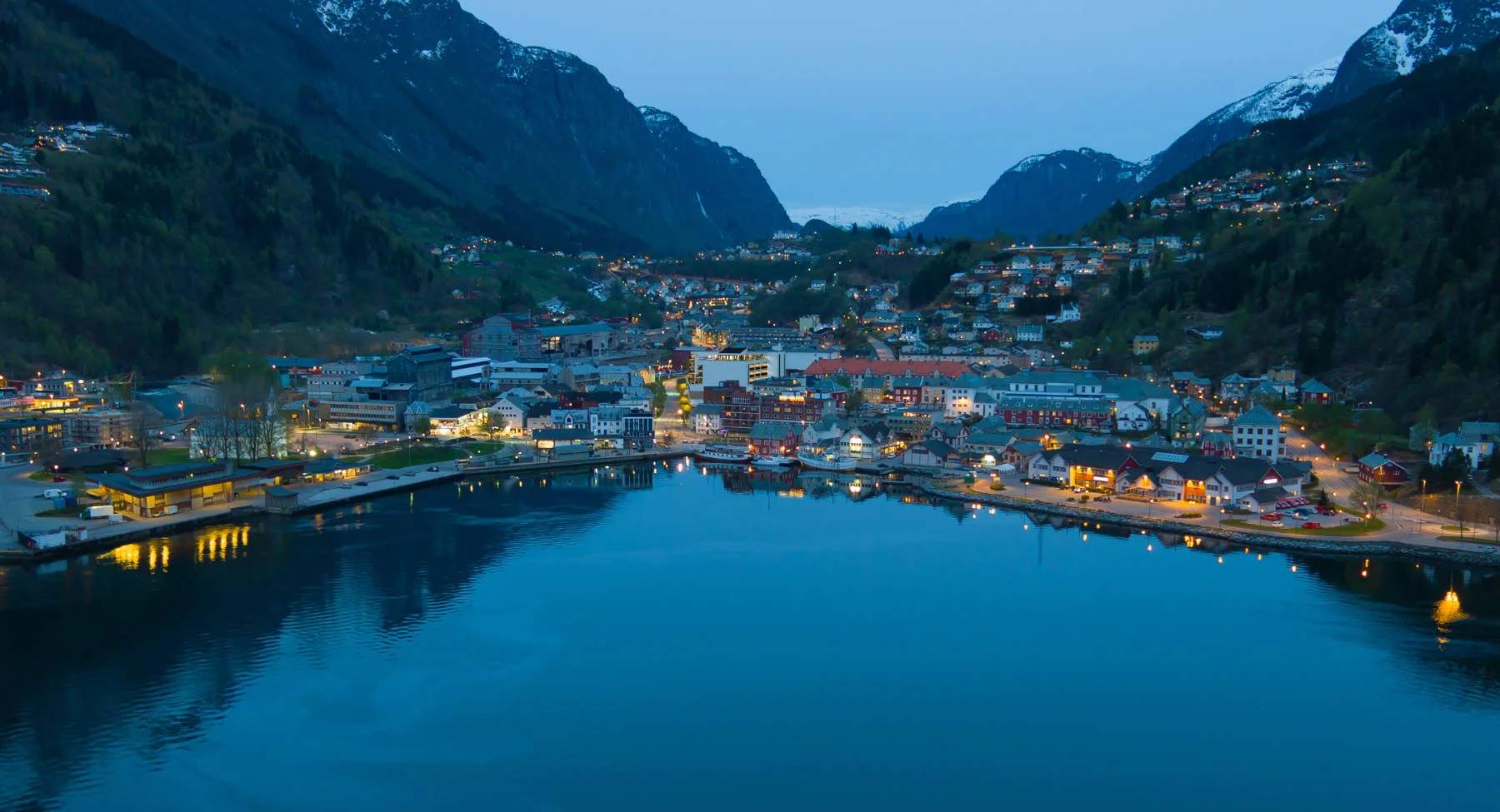 Fjorden og sentrum i blå time, med lysene som speiler seg i vannet. Opplev stemningen i nærområdet til Domus Gaarden.