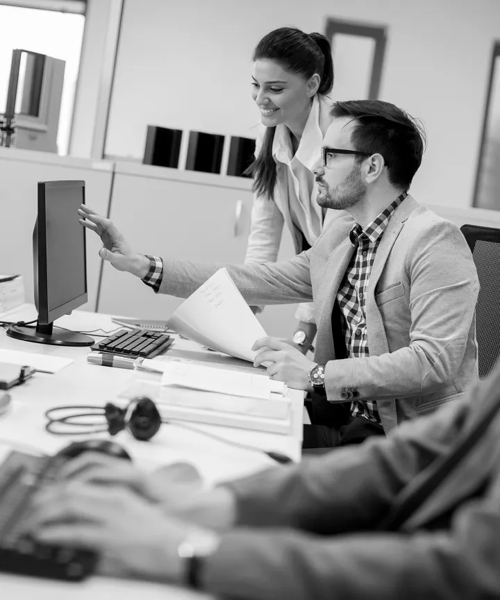 Colleagues reviewing work at a desktop computer