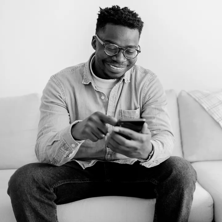 Man using a mobile phone while seated on a sofa