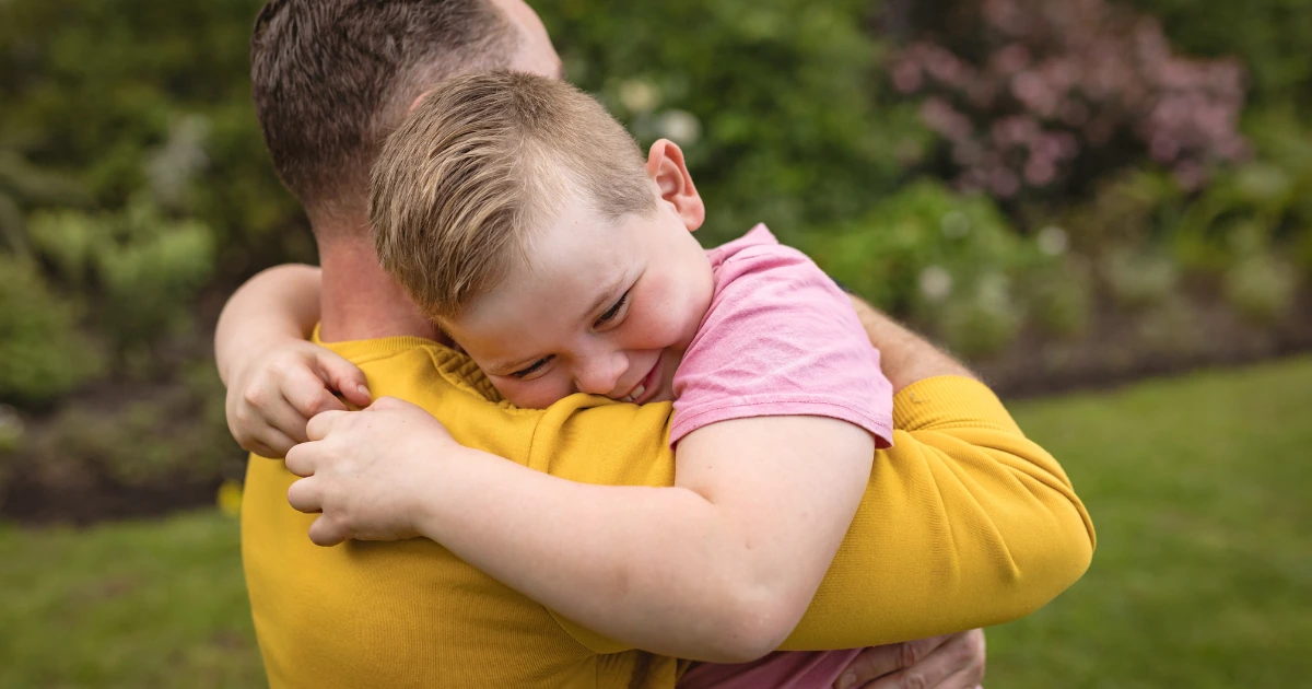 Child hugging an adult outdoors