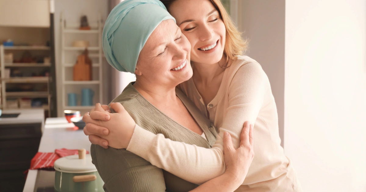 Woman wearing a headscarf being embraced by another woman at home